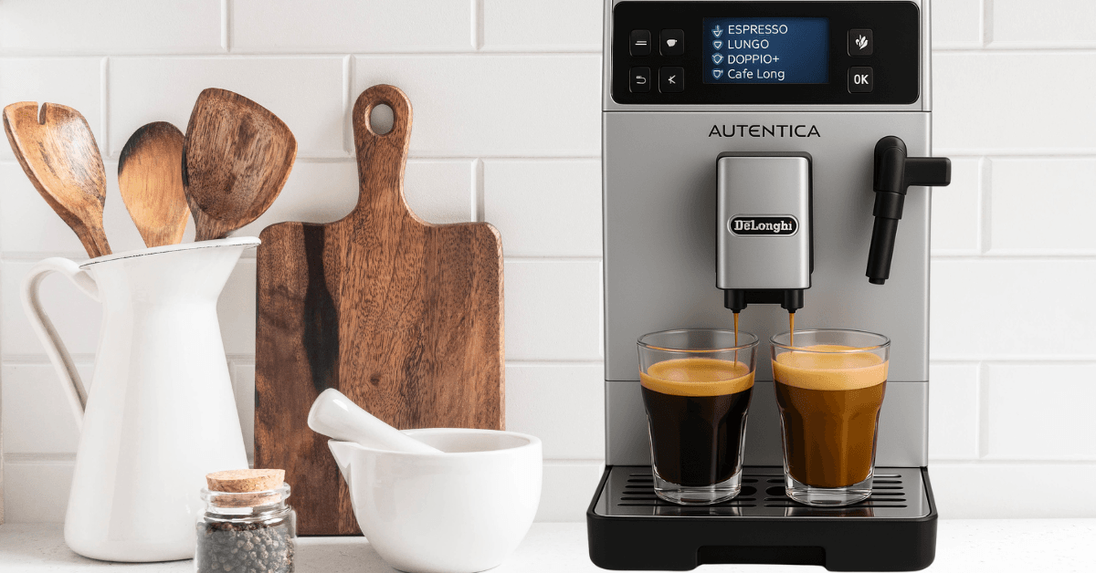 De’Longhi Autentica Plus Kaffeevollautomat mit zwei Gläsern Kaffee auf der Arbeitsplatte in einer modernen Küche mit Holzutensilien. De’Longhi Autentica Plus Kaffeevollautomat mit zwei Gläsern Kaffee auf der Arbeitsplatte in einer modernen Küche mit Holzutensilien.