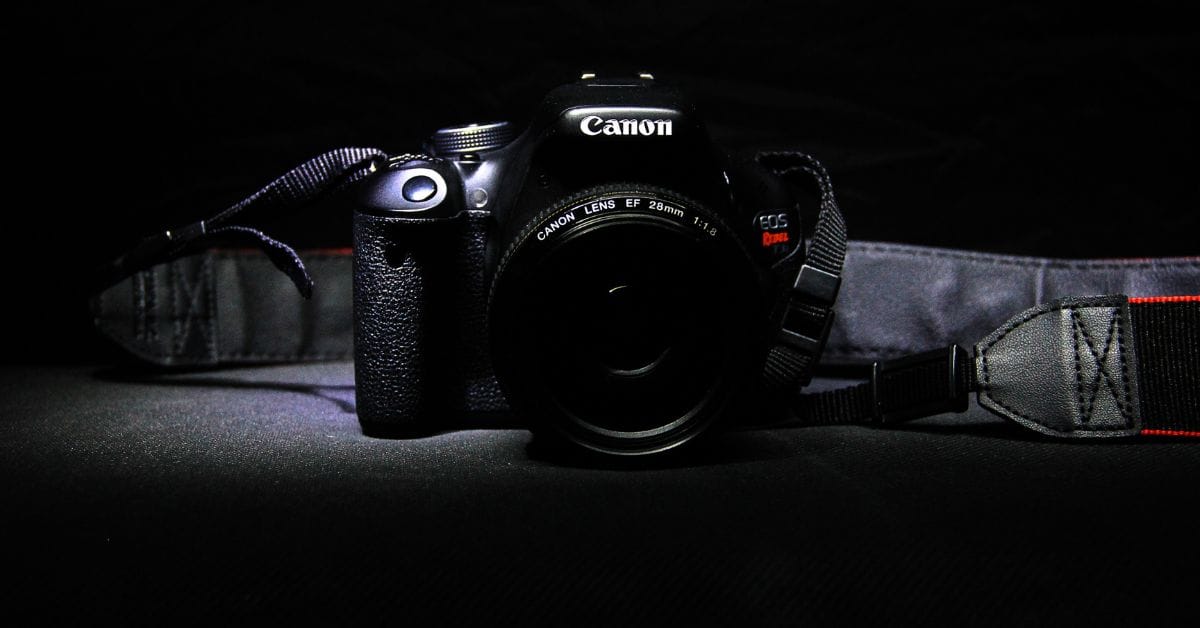 Canon DSLR-Kamera bei schwachem Licht mit Objektiv und Tragegurt.