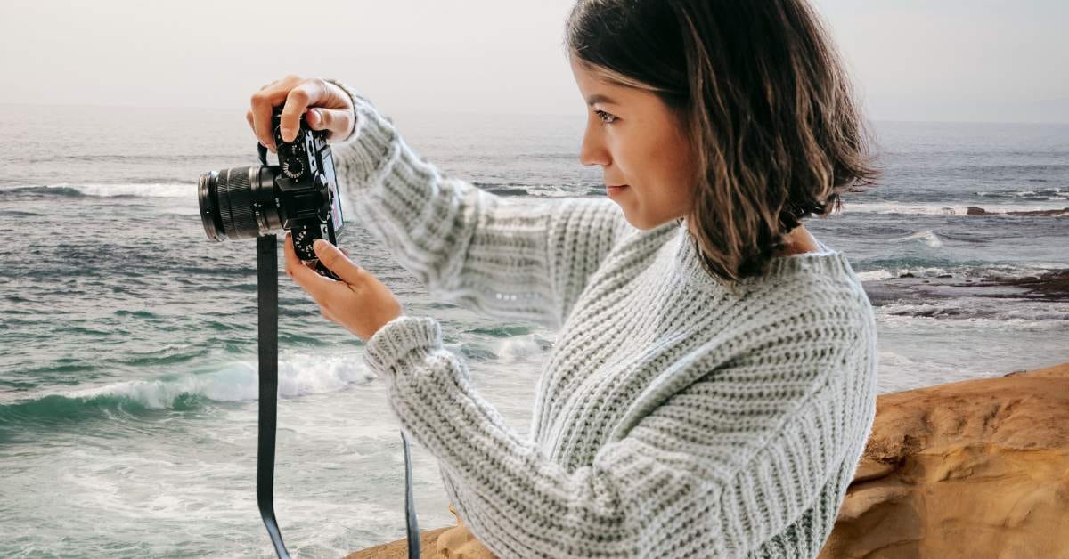 Junge Frau hält eine Kamera am Meer – Einstieg in die Fotografie für Anfänger