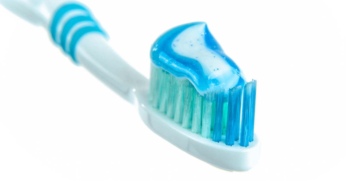 Zahnbürste mit blauer Zahnpasta – Nahaufnahme auf weißem Hintergrund